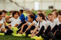 Children sitting on the pitch at Monster Kickabout 2021